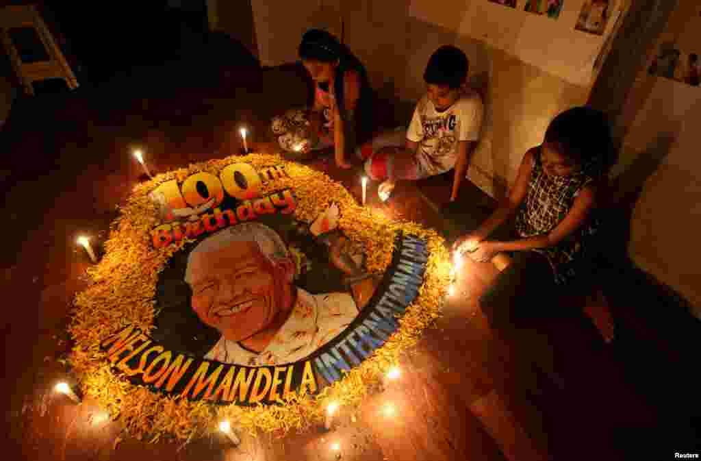 Children light candles beside a painting commemorating the late Nelson Mandela, South Africa&#39;s first black president, on the 100th anniversary of his birth, at an art school in Mumbai, India.