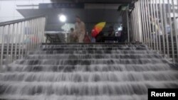 Air banjir mengalir deras di tangga stasiun bawah tanah Beijing akibat badai dan hujan lebat, Sabtu (21/7).