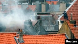 Un policier belge masqué a pris position sur un toit près du lieu où des coups de feu ont été entendus lors d'une perquisition de la police d'une maison dans la banlieue de Forest, près de Bruxelles, 15 mars 2016. 