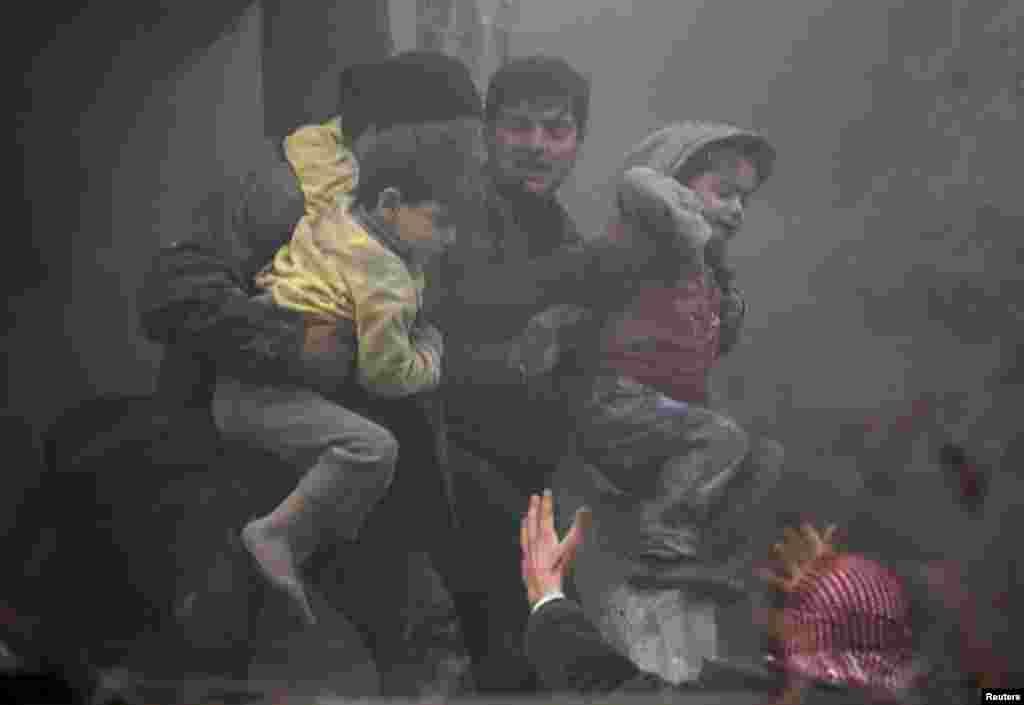 7일 시리아 정부군의 공습으로 다마스쿠스 인근 마을이 폐허가 된 가운데, 사람들이 부상당한 소년을 돕고 있다.