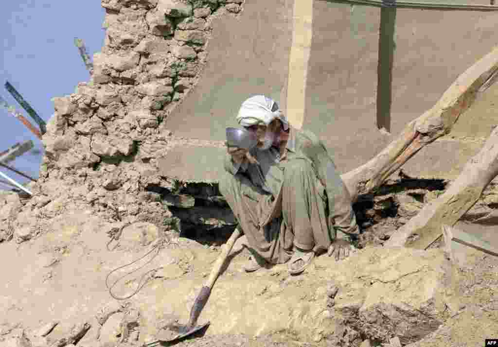 Seorang korban gempa bumi di Pakistan melepaskan dahaganya  di rumahnya yang runtuh di daerah Dhall Bedi Peerander, distrik Awaran, yang hancur akibat gempa. Puluhan ribu korban gempa menunggu bantuan seiring dengan meningkatnya jumlah korban tewas mencapai hampir 350 jiwa. 