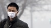 A man wears a mask as he walks to cross a street shrouded by haze in Beijing, China, Jan. 10, 2012.