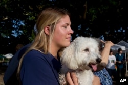 Heidi Guillory hugs her dog Cohen during a moment of silence for shooting victims in Lafayette, La., July 25, 2015.