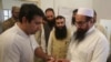 An election officer marks a thumb of Hafiz Saeed, right, head of the Pakistani religious party Jamaat-ud-Dawa, at polling station in Lahore, Pakistan, July 25, 2018. 