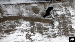 Un habitant de Washington déblaie la neige devant chez lui, samedi 23 janvier 2016. (AP Photo/Jon Elswick)
