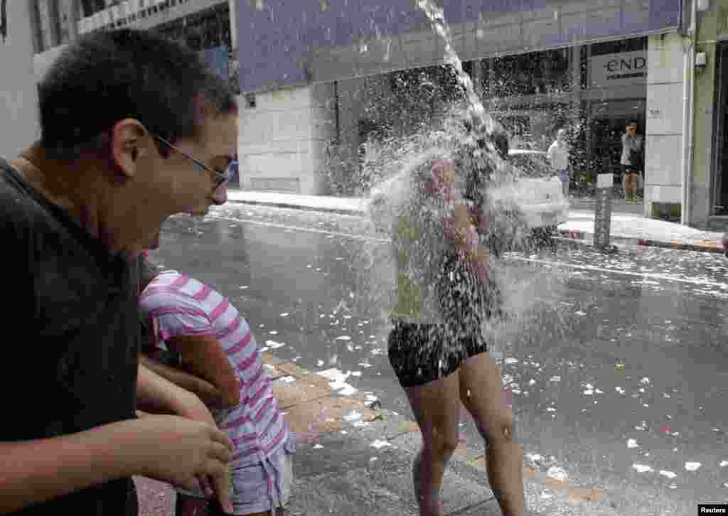 A woman is soaked at Montevideo financial district. To mark the last working day of the year, workers throw water at people and discard old calendars.