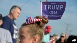 A girl shows her support for President Donald Trump while waiting in line for his campaign rally at Ocala International Airport, in Ocala, Florida, Oct. 16, 2020. 