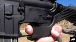 FILE - In this Oct. 4, 2017 file photo, shooting instructor Frankie McRae demonstrates the grip on an AR-15 rifle fitted with a bump stock at his 37 PSR Gun Club in Bunnlevel, N.C.