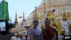 Turis berpose bersama seorang biksu di Shwedagon Pagoda, Rangoon, Burma. (Foto: AFP/Soe Than Win)
