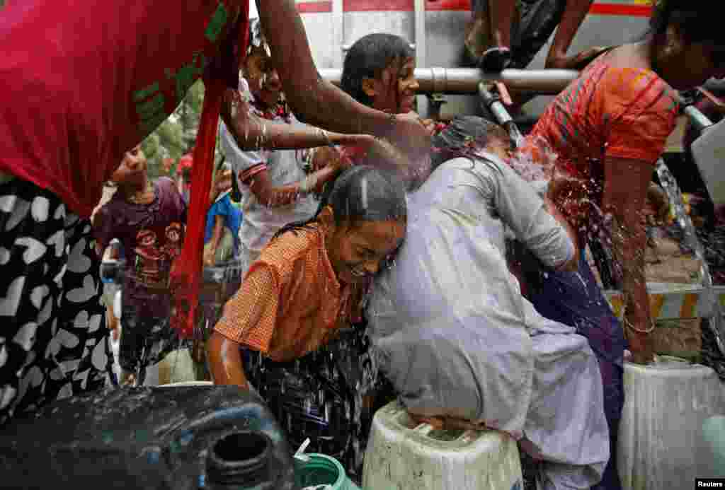Girls get drenched as they try to fill empty containers with water from a municipal tanker on a hot summer day in New Delhi, India.