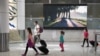 FILE - Travelers wearing protective face masks make their way through the arrivals section of the international terminal of Kingsford Smith International Airport the morning after Australia implemented an entry ban on non-citizens and non-residents.