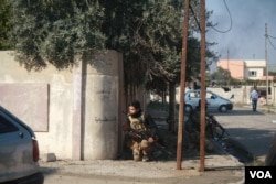 Iraqi soldiers peers around a corner to a road in range of IS sniper fire from across the river. Locals say as Iraqi forces take back areas, life is starting to go back to normal in many parts of eastern Mosul, Jan. 29, 2017. (H. Murdock/VOA)