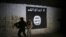 FILE - In this March 1, 2017 photo, an Iraqi soldier inspects a tunnel, adorned with an Islamic State group flag. 