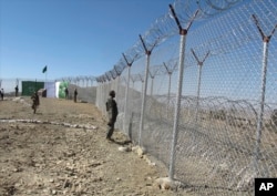 FILE - Pakistani soldiers stand guard at a fence between Pakistan and Afghanistan at Angore Adda, Pakistan, Oct. 18, 2017. Pakistan's military says the fencing and guard posts along the border with Afghanistan help prevent militant attacks.
