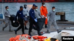 Personel DVI dan angkatan laut membawa tas berisi bagian tubuh penumpang Sriwijaya Air penerbangan SJ-182 yang jatuh ke laut, di pelabuhan Tanjung Priok, Jakarta, 13 Januari 2021. (Foto: Reuters)