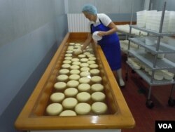 The cheese wheels are immersed in salt brine before being cured in a refrigeration room. (VOA/J. Taboh)