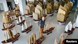 Planner and explorer Jin Feibao poses for pictures with his models of the full fleet led by Ming Dynasty eunuch explorer Cheng Ho, also known as Zheng He, in Kunming, Yunnan province, July 11, 2014.