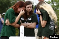 Sobrevivientes se reúnen en un lugar donde se colocaron 10 cruces en Santa Fe, Texas, en honor de las víctims de un tiroteo en una escuela secundaria la semana pasada. Mayo 21, 2018.