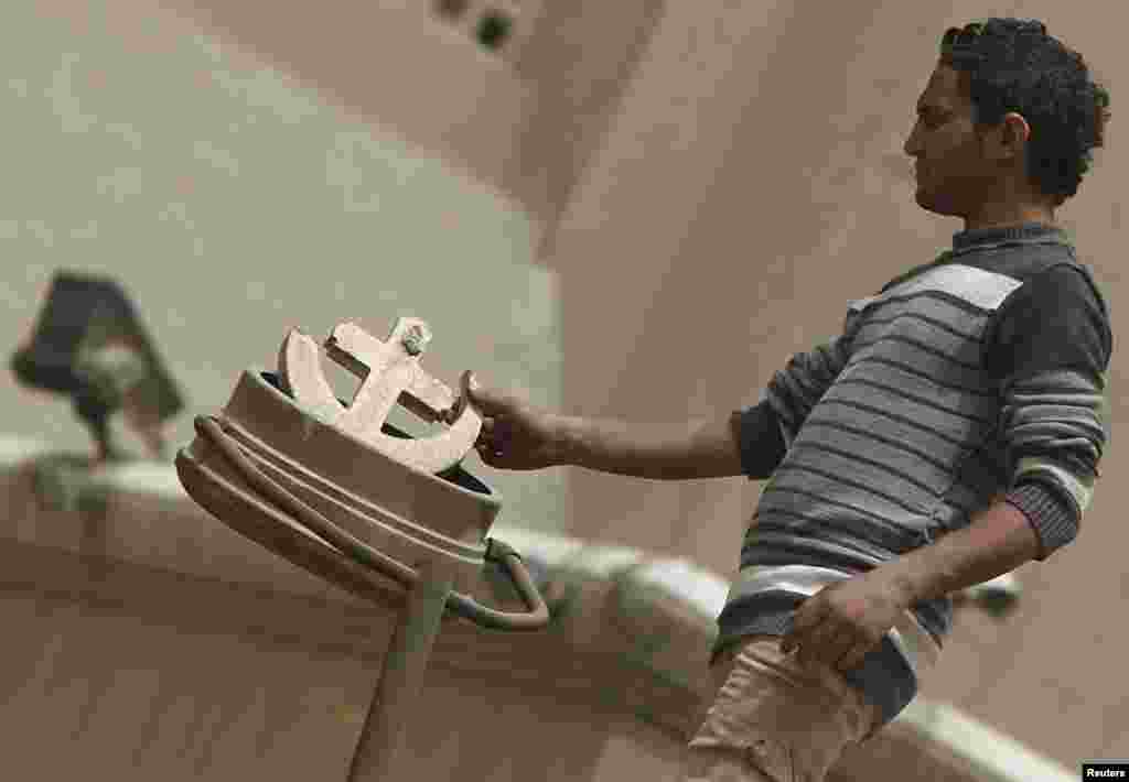 Seorang warga Kristen Koptik memegang lambang Salib dan Bulan Sabit yang patah, lambang persatuan nasional antara Kristen dan Muslim, yang sebelumnya terpasang di gereja Katedral di Kairo.&nbsp; Kekerasan sektarian sedang terjadi di Mesir menewaskan sedikitnya 2 orang.&nbsp; 