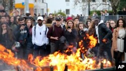 Estudiantes observan un contenedor de basura en llamas afuera de su escuela en Bayonne, en el suroeste de Francia, el jueves 6 de diciembre de 2018.