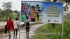 FILE - People walk past a billboard warning residents to stop the stigmatization of Ebola survivors, in Kenema, eastern Sierra Leone. On Nov. 7, WHO will declare the country is Ebola-free after going 42 days without any new infections.