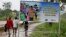 FILE - People walk past a billboard warning residents to stop the stigmatization of Ebola survivors, in Kenema, eastern Sierra Leone. On Nov. 7, WHO will declare the country is Ebola-free after going 42 days without any new infections.