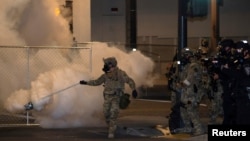 A federal law enforcement officer, deployed under the Trump administration's new executive order to protect federal monuments and buildings, uses tear gas during a protest over racial inequality in Portland, Oregon, July 17, 2020.