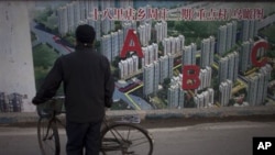 2013年1月北京一处工地旁有人观看居民楼鸟瞰图。何清涟写道，中国房地产价格攀升与全国数百座鬼城同时出现。