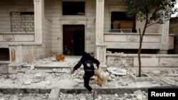 A Syrian boy runs away with a dead chicken he grabbed from the debris of a building hit by an airstrike in Idlib, Syria, Feb. 28, 2020.