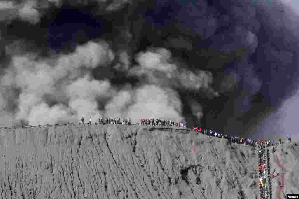 Warga berdiri di pinggiran kawah untuk menonton letusan Gunung Bromo di Probolinggo, Jawa Timur.