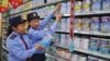 FILE - Chinese commercial law enforcement personnel inspect milk powder products at a supermarket in Lianyungang, Jiangsu province, China.