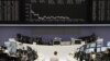 Traders work at their desks in front of the DAX board at the Frankfurt stock exchange, May 14, 2012. 