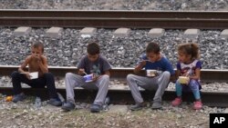 মেক্সিকোর হুহুয়েটোকাতে উত্তরগামী মালবাহী ট্রেনে চড়ার জন্য অভিবাসন-প্রত্যাশী শিশুরা রেলপথে বসে খাচ্ছে। ১২ মে, ২০২৩।