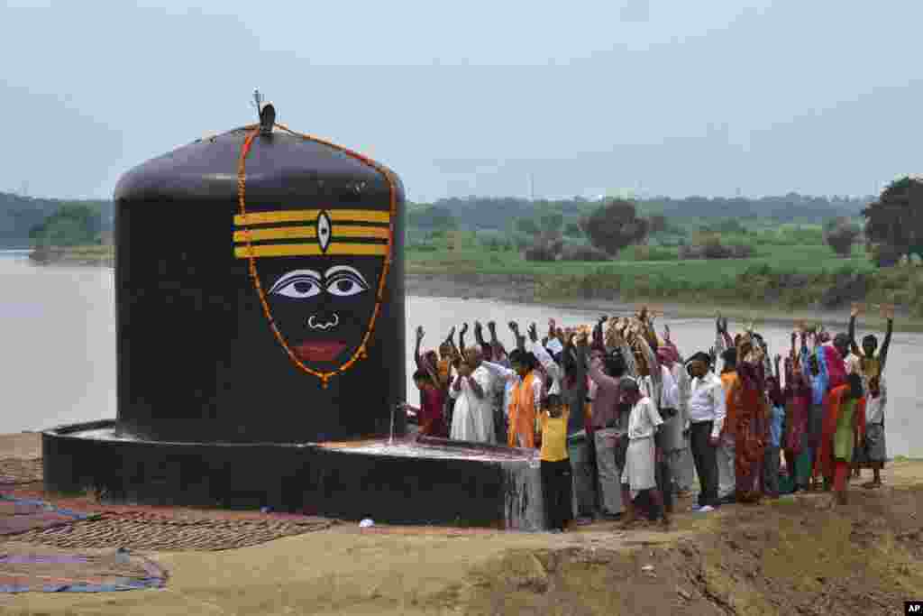 Para pemuja dewa Hindu Siwa mengangkat tangan mereka sambil melantunkan nyanyian relijius saat menyembah &#39;lingam&#39;, yang baru selesai dipasang di tepi sungai Yamuna di Agra, India. (AP Photo/Pawan Sharma)