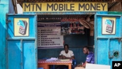 In this photo taken Tuesday, Sept. 10, 2019, a man sits in his mobile money kiosk which specializes in sending money from South Sudan to Uganda, in the capital Juba, South Sudan