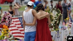 FILE - A couple spend a quiet moment at a makeshift memorial honoring the victims of the Pulse nightclub mass shooting, June 20, 2016, in Orlando, Fla.