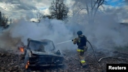 资料照片：乌克兰尼古拉耶夫市一名消防人员在俄罗斯导弹攻击后给一辆汽车灭火。(2024年3月17日）
