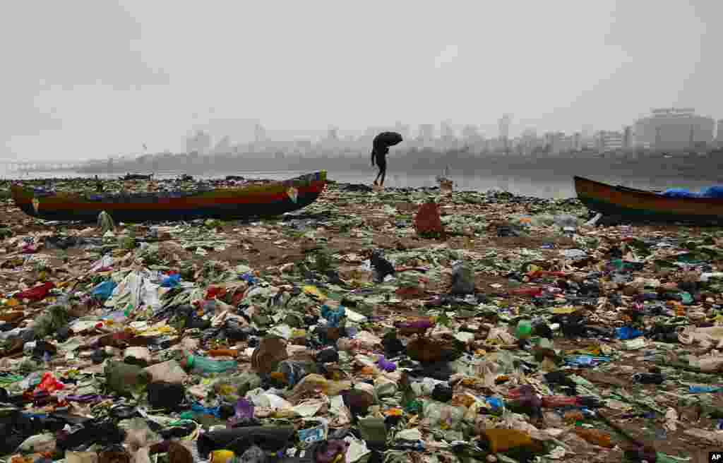 Seorang nelayan India berjalan di pantai Laut Arabia yang penuh dengan sampah di kota Mumbai.
