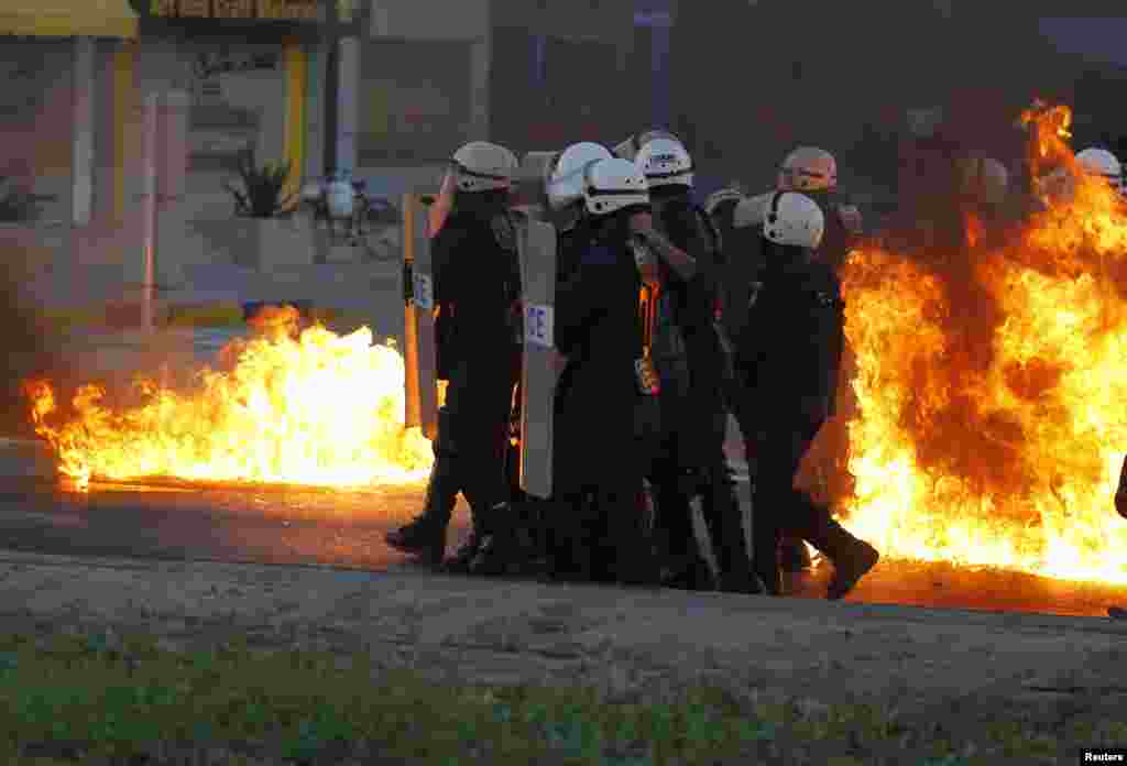 Polisi anti huru-hara bergerak maju di belakang perisai mereka sementara api dari bom Molotov yang dilempar oleh para demonstran anti-pemerintah telah menyebabkan kebakaran di sekeliling mereka ketika terjadi bentrokan di Budaiya, Manama bagian barat, Bahrain.
