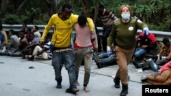 Des migrants africains portent sur leurs épaules leurs camardes malades à leur arrivée au centre de transit des migrants à Ceuta, Espagne, 17 février 2017.