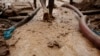 A man walks on special carpets that are used to filter earth and water in search of gold at an illegal mine site, file photo. 