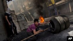 Seorang warga Palestina bersiap hendak membakar ban dalam bentrokan melawan pasukan Israel (tidak dalam gambar) di Hebron, Tepi Barat (3/4). Israel untuk pertama kalinya membalas tembakan roket Gaza sejak gencatan senjata tidak resmi, November lalu.