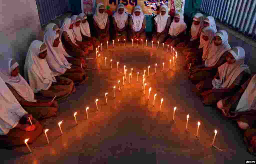 Anak-anak sekolah menyalakan lilin berbentuk pita dalam kampanye peningkatan kesadaran HIV/AIDS sebelum Hari AIDS Sedunia di Ahmedabad, India (30/11). (Reuters/Amit Dave)