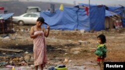 지난해 3월 중국과 접경지역인 미얀마 코캉의 난민캠프에서 한 여성이 머리를 감고 있는 모습을 어린 딸이 지켜보고 있다.