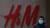A man wearing a face mask walks by a Swedish fashion brand H&M store outlet in Beijing, March 25, 2021. 