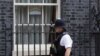 A police officer walks past a drawing of a rainbow with the words "we are in this together" displayed in one of the windows of 10 Downing Street in London, April 9, 2020. 