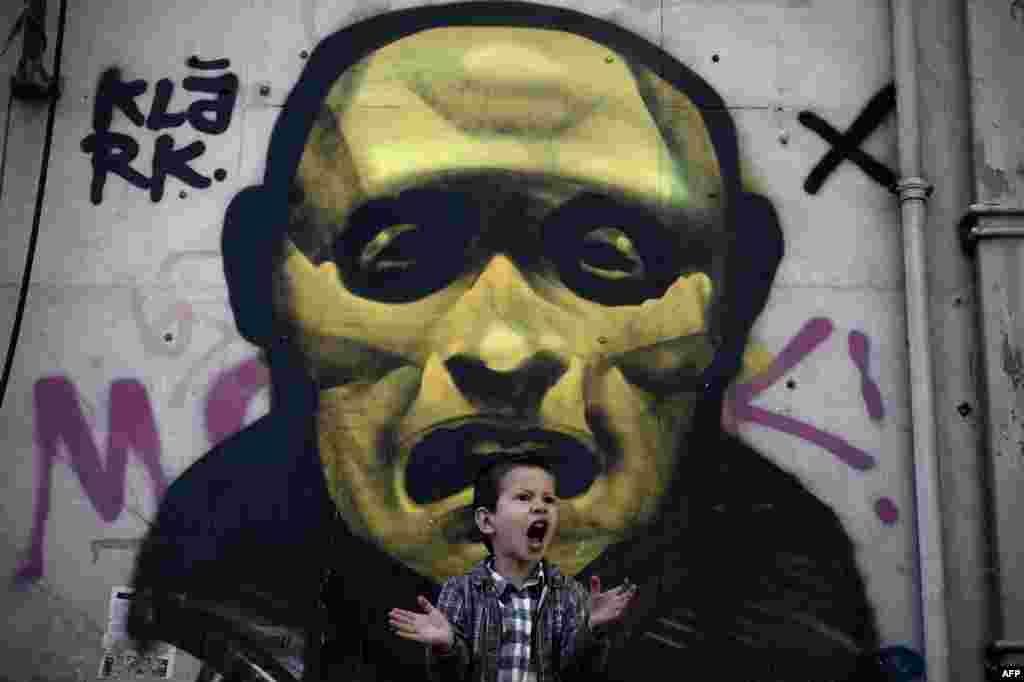 Seorang anak laki-laki Yunani berteriak di depan sebuah lukisan di jalanan ibukota Athena.