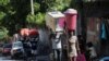 People carry their belongings along a street as they flee their homes from gang violence, in Port-au-Prince, Haiti, Oct. 26, 2024.