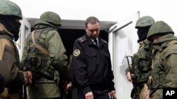 Rus əsgərləri olduqları güman edilən uniformasız “yaşıl adamlar”-ın əhatəsində ukraynalı donanma zabiti Krımdakı hərbi bazanı tərk edir.