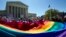 FILE - Demonstrators stand in front of a rainbow flag of the Supreme Court in Washington.